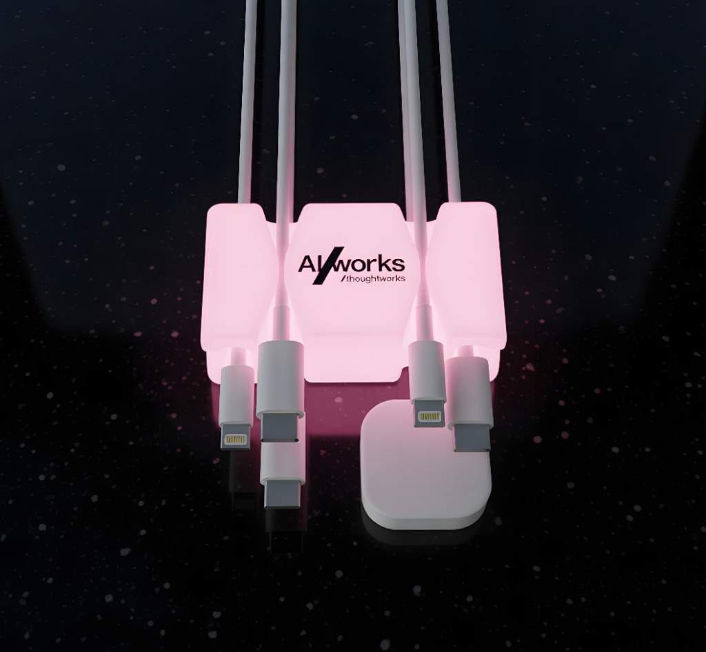Pink CordBrick Glow with an AI Works Thoughtworks logo holding charging cables